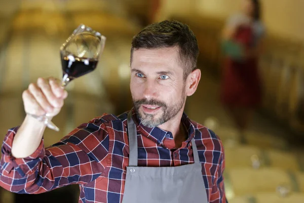 wine producer holding wineglass up to the light
