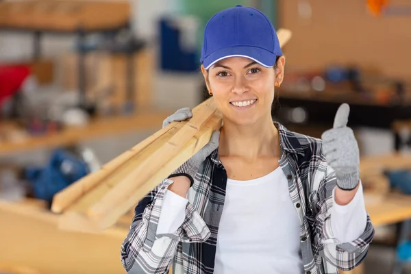 Jovem Carpinteiro Feminino Concentrado Segurando Pranchas Madeira — Fotografia de Stock