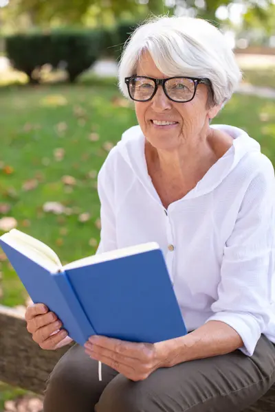 Eine Frau Liest Auf Der Bank Ein Buch — Stockfoto