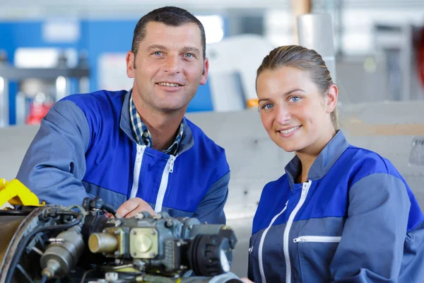 a man mechanic and woman looking at camera