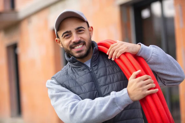 Happy Construction Worker Holding Red Pipes — Stock Photo, Image