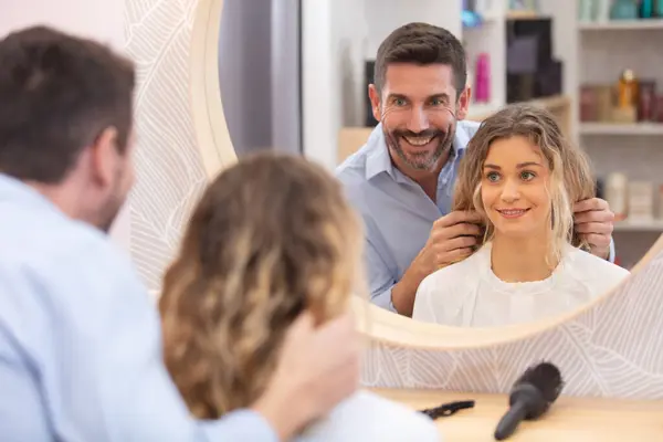 male hairdresser in discussion with female client looking in mirror