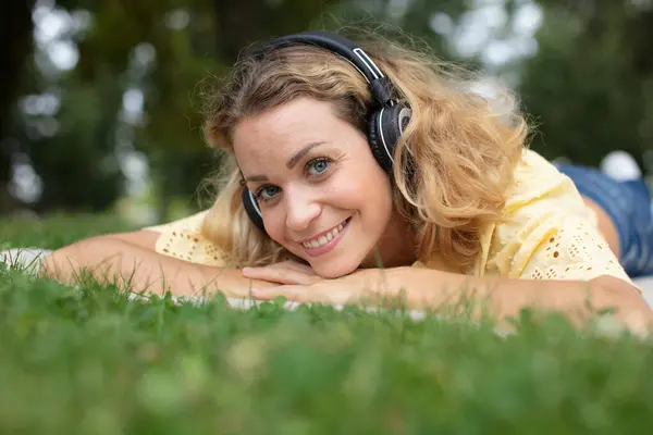 Kadının Kafasında Çime Uzanmış Kulaklık Dinlerken — Stok fotoğraf