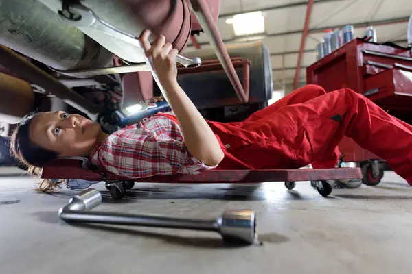 女性汽车修理工工作下面车在车库里 — 图库照片