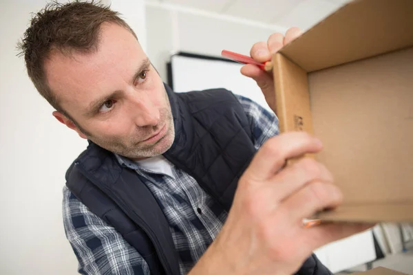 man making a pencil mark on cardboard box