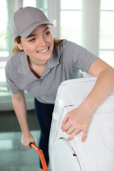 キッチンで洗濯機を運ぶ若い幸せな女性モーバー — ストック写真