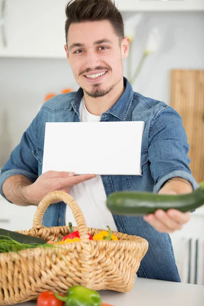 man holding white board in kitchen