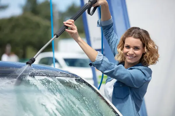 woman standing with spray foam cleaning her car