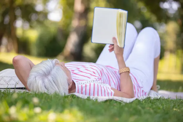 mature woman reading a book in the garden