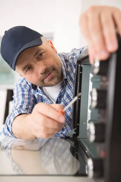 man repairs microwave oven with a screwdriver