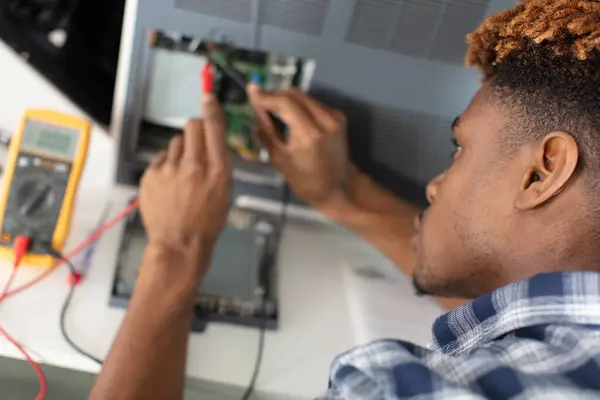 young man working with screwdriver in service center