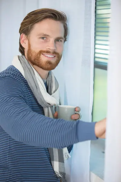 Człowiek Stał Przy Oknie Trzymając Filiżankę Kawy — Zdjęcie stockowe