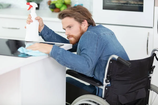 handicapped man sitting on wheelchair cleaning kitchen