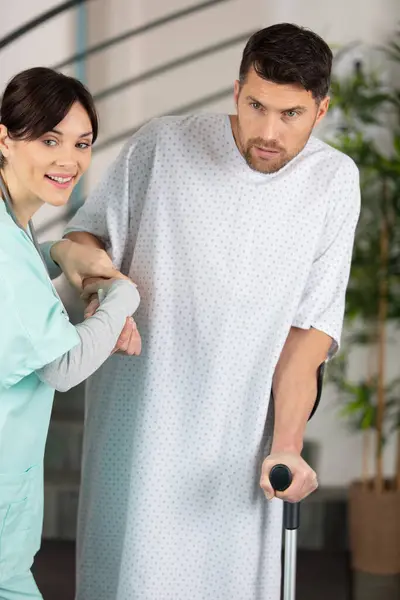 Kind Female Nurse Helping Male Patient Ctutches — Stock Photo, Image
