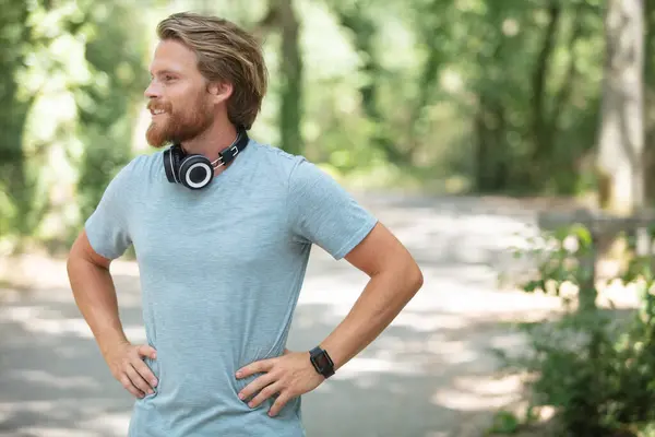male jogger wearing headphones taking a rest