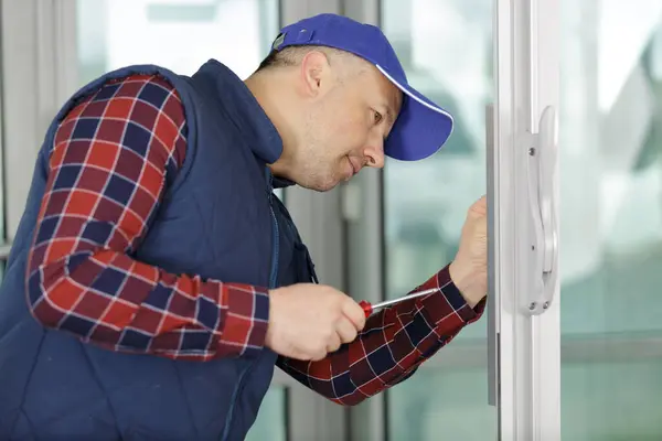 worker man installs windows with screwdriver