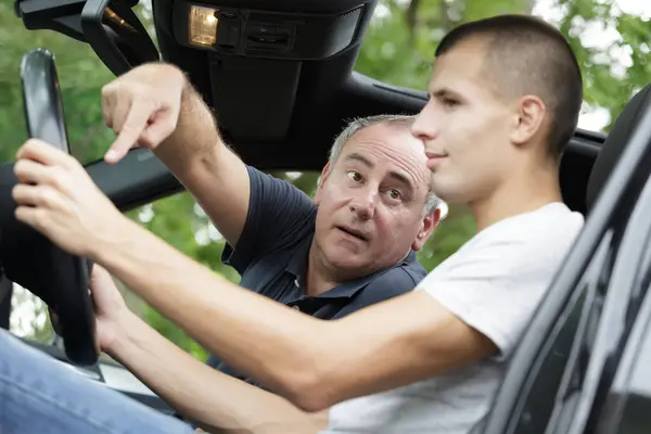 driving teacher pointing at steering wheel