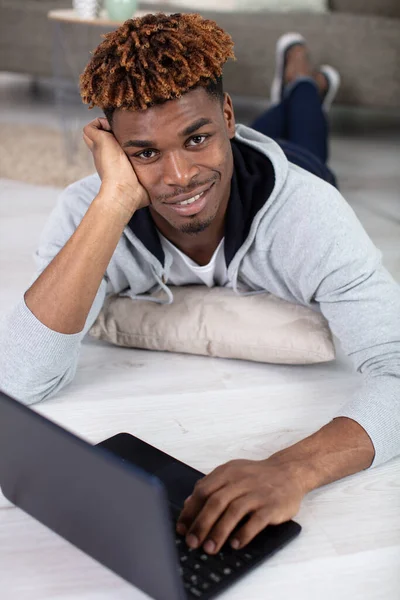 attractive smiling chill guy is browsing at his laptop