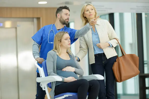pregnant woman on wheelchair with doctor and mum in hospital