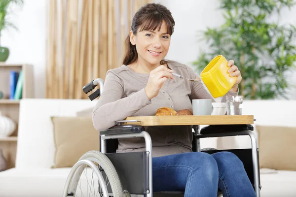 pretty disable woman in a wheel chair having breakfast