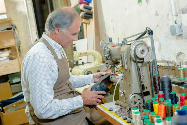 a man is stitching shoe