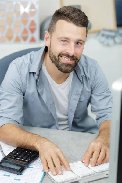 happy man calculates working on desk at office
