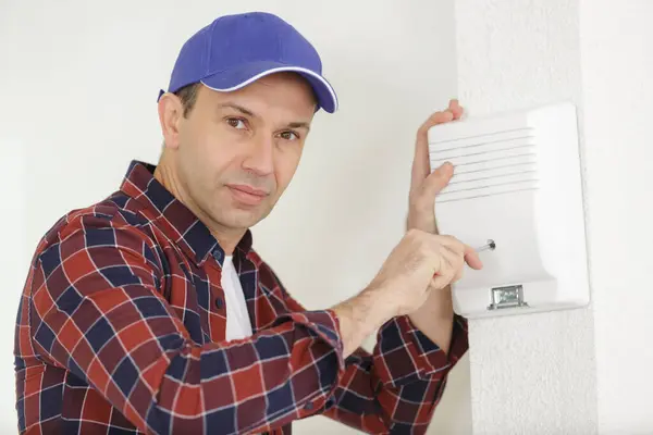 男电工在墙上安装安全系统门传感器 — 图库照片