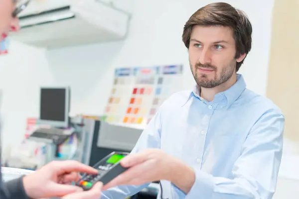 man paying sales assistant with credit card in shop