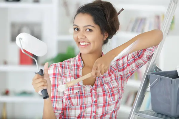 woman applying glue on wallpaper