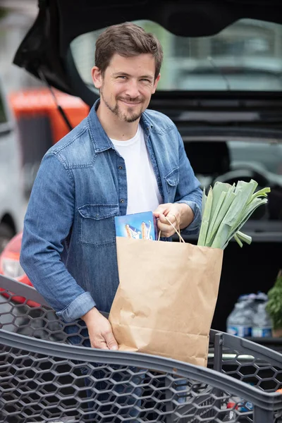 Uśmiechnięty Samiec Wkładający Papierowe Torby Jedzeniem Bagażnika Samochodu — Zdjęcie stockowe