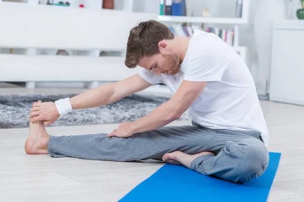 Jonge Man Zittend Een Trainingsmat Stretching — Stockfoto