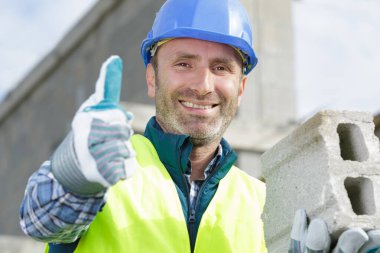 man showing thumb-up builds a brick wall clipart