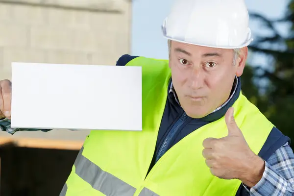 handsome worker shows thumbs-up while holding a blank board