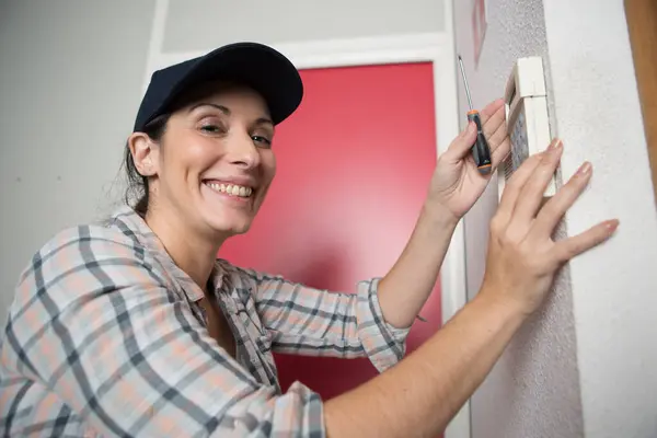 happy woman plumber fixing a thermostat