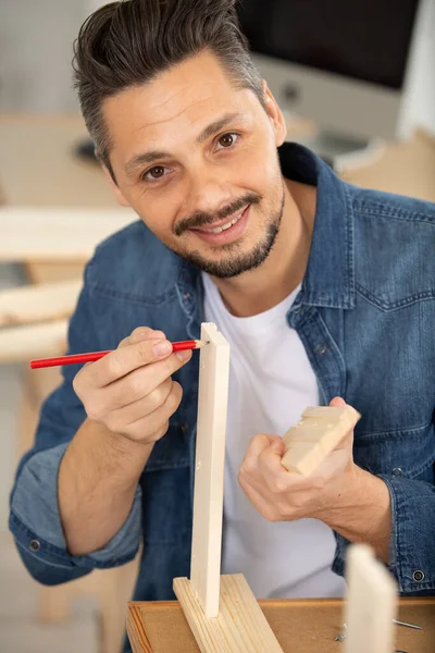 carpenter using pencil to mark wood pieces