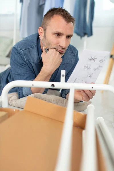 puzzled man reading instructions to assemble furniture