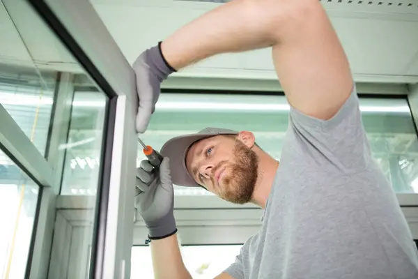 handyman using screwdriver to install a window