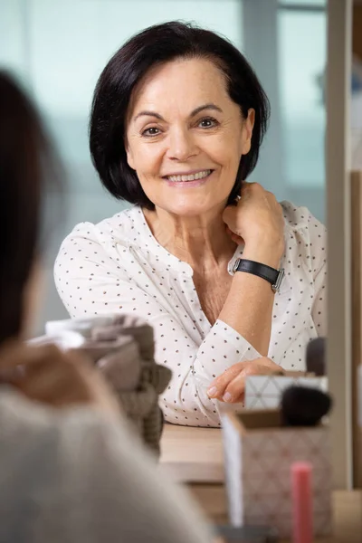 senior woman smiling into the mirror