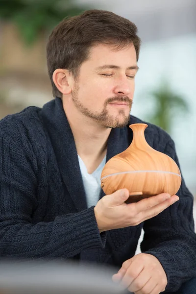 man is smelling essential oil from an aroma diffuser