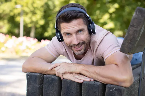man on park bench wearing headphones