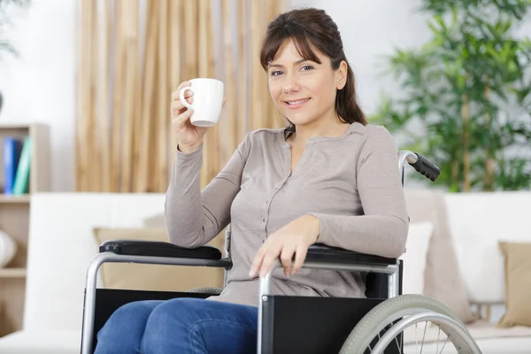 disabled woman in wheelchair drinking coffee at home