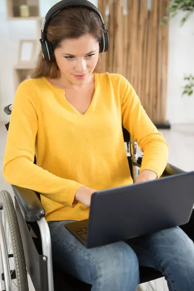 Dizüstü Bilgisayar Kullanan Kulaklık Takan Tekerlekli Sandalyedeki Çekici Kadın — Stok fotoğraf