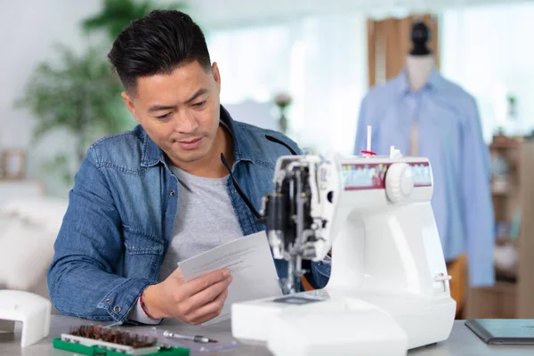 mechanic repairing sewing machine reads instructions