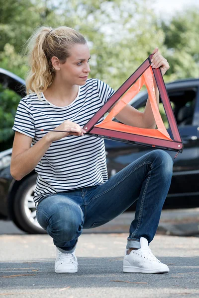 woman assembling the car warning triangle