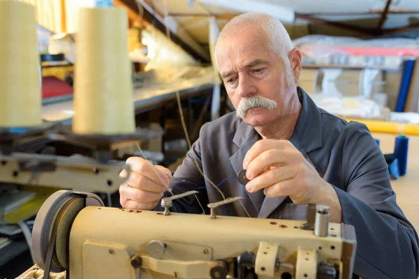 man threading up sewing machine