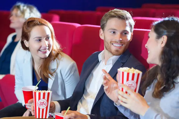 three young people chatting in cinema seats