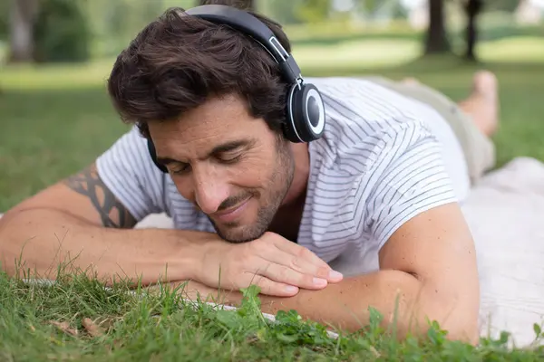 男人在草地上听着音乐 — 图库照片