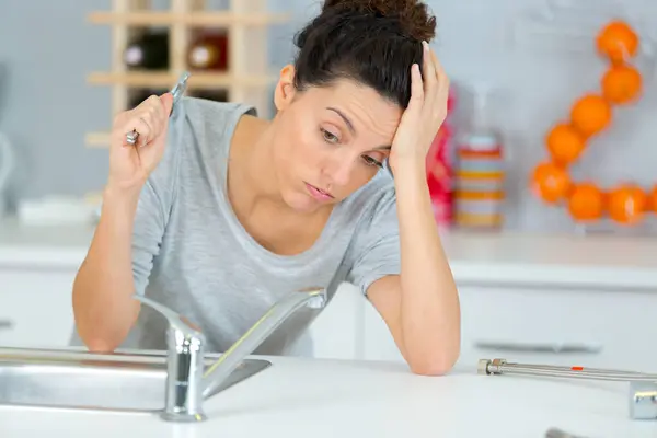 young woman frustrated fixing sink