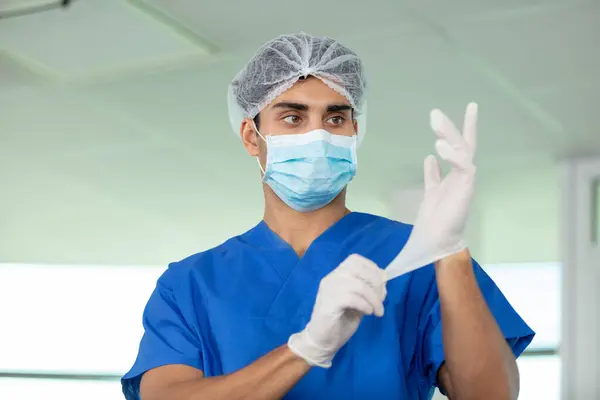 male surgeon putting on latex gloves in preparation