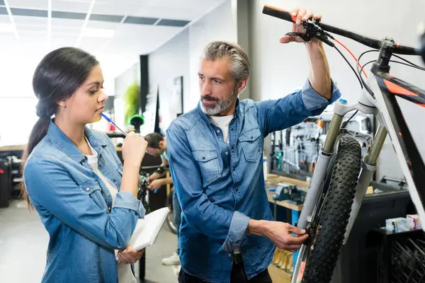 mechanic with female apprentice looking at off-road bicycle